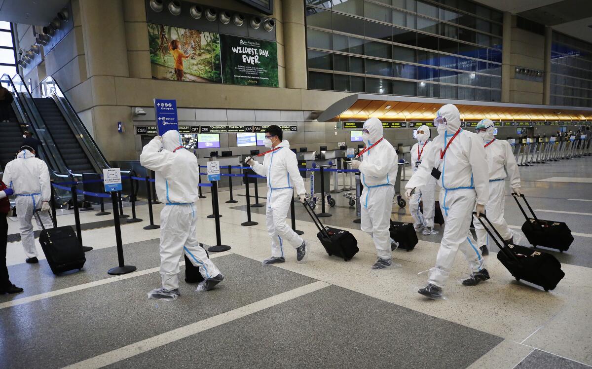 The crew for a Hainan Airlines flight walks through the Tom Bradley International Terminal at Los Angeles International Airport, which is now requiring travelers to wear face coverings during the coronavirus outbreak.