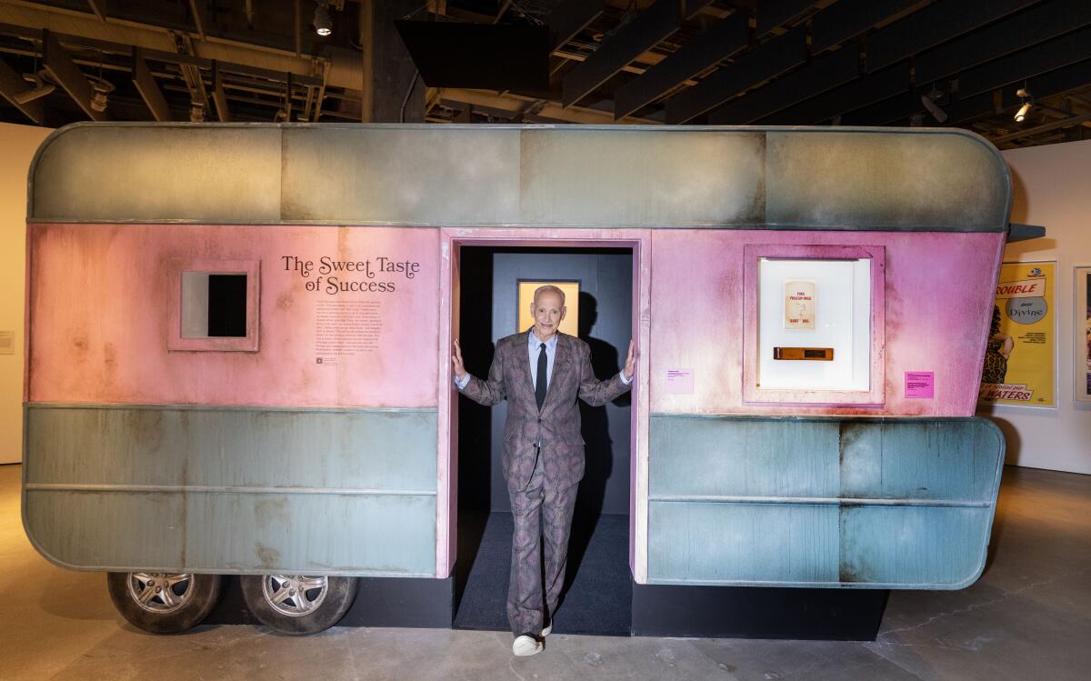 A man stands in front of a pink trailer.