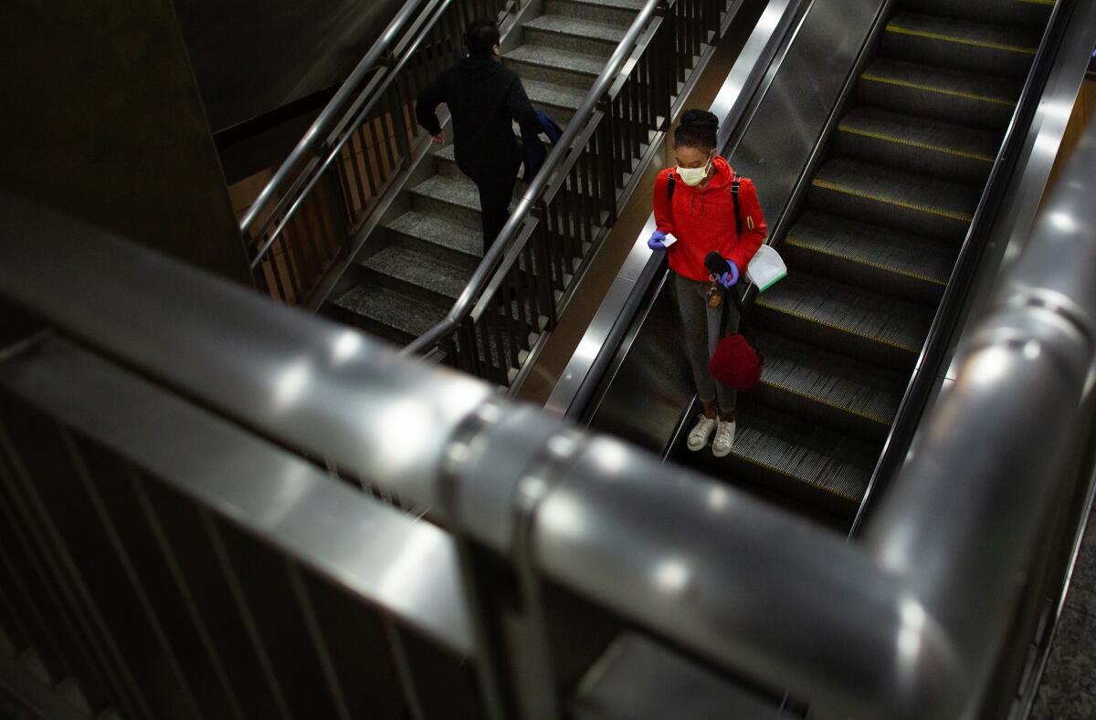 A woman wearing a mask rides the escalator in the Hollywood/Highland Metro Station on Thursday in Los Angeles.