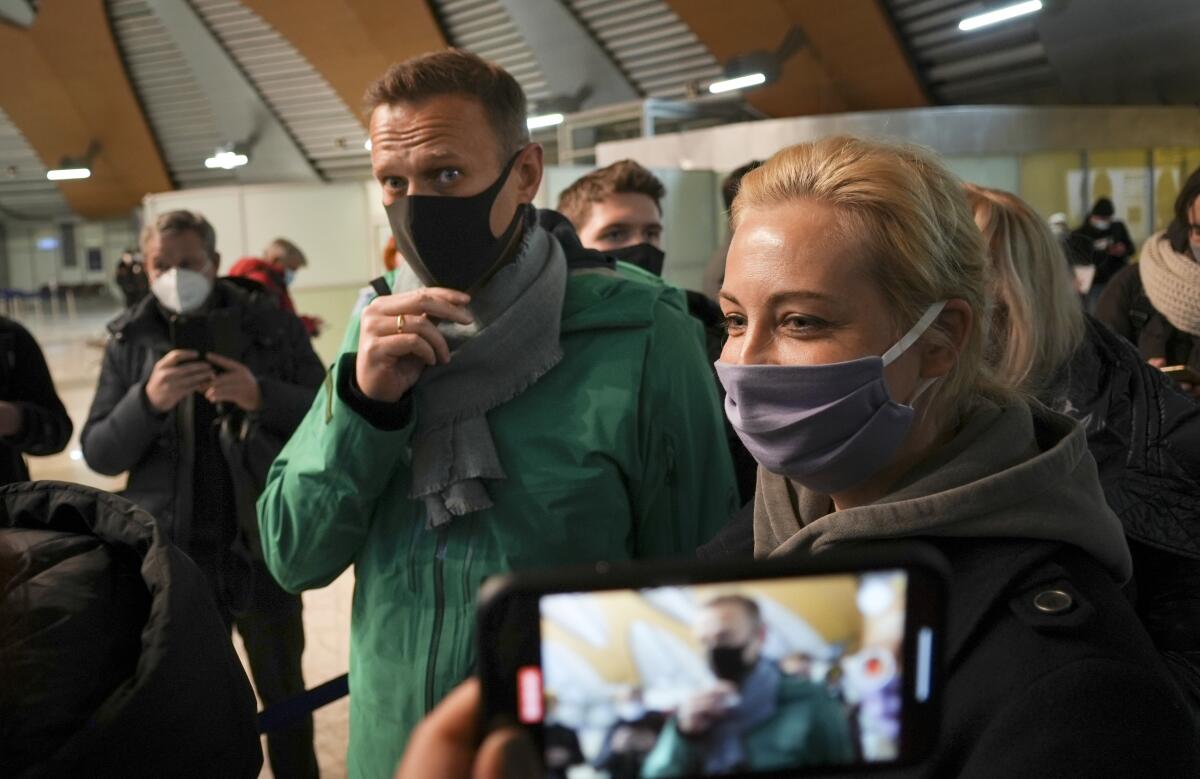 Alexei Navalny and his wife, Yulia, wear masks as they stand in line