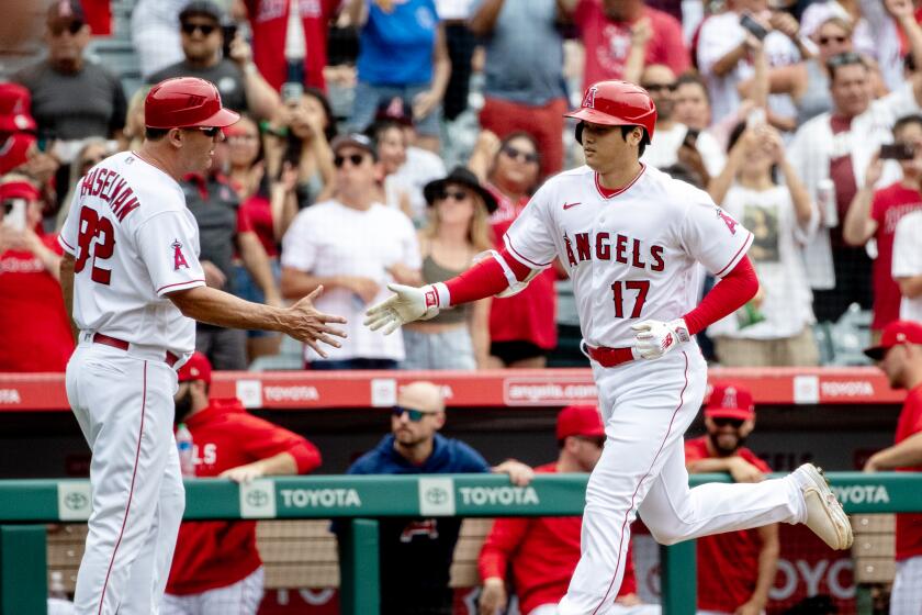 ANAHEIM, CA - JULY 23, 2023: Los Angeles Angels DH Shohei Ohtani (17) gets a hand shake from Los Angeles Angels third base coach Bill Haselman (82) after his solo homer ties the game against the Pittsburgh Pirates in the first inning on July 23, 2023 in Anaheim, California. (Gina Ferazzi / Los Angeles Times)