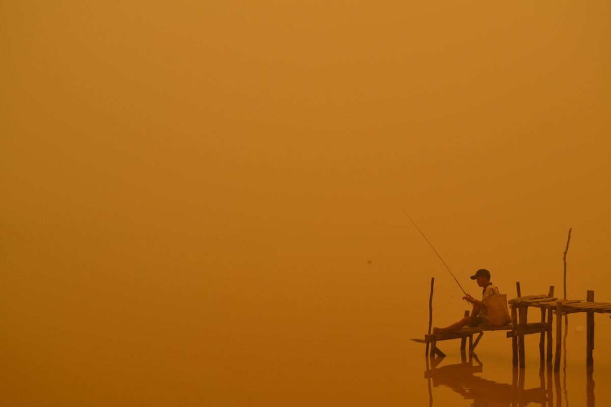 A resident fishes by the river in Palangkaraya, one of the cities worst-hit by haze in Indonesia's central Kalimantan province.