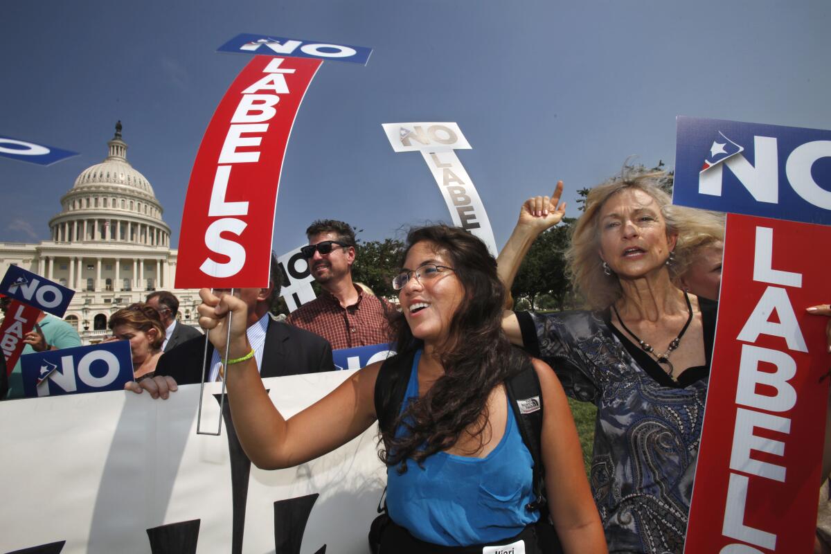 Two women hold signs saying “No Labels” at a rally in front of the U.S. Capitol.