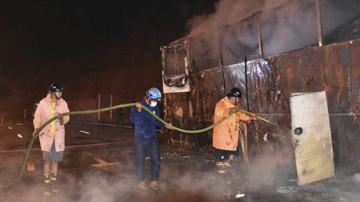 Firefighters douse flames after a fire aboard a double-decker bus killed 20 people in Thailand's Tak province on March 30.