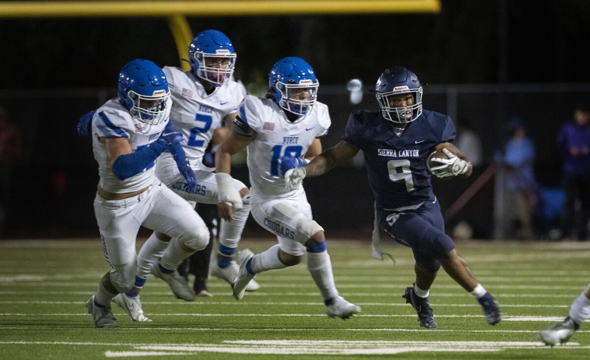 Sierra Canyon running back Jason Jones tries to evade Norco's Andrew Parker (25), Logan Grier (2), and Darius Ward (10).