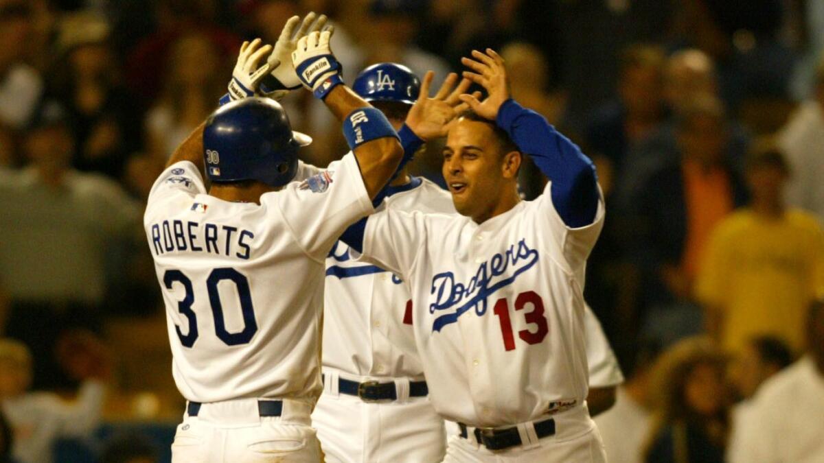 Dave Roberts is congratulated by Alex Cora after scoring a run.