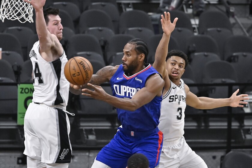 Clippers' Kawhi Leonard passes the ball as he is defended by San Antonio Spurs' Drew Eubanks and Keldon Johnson.