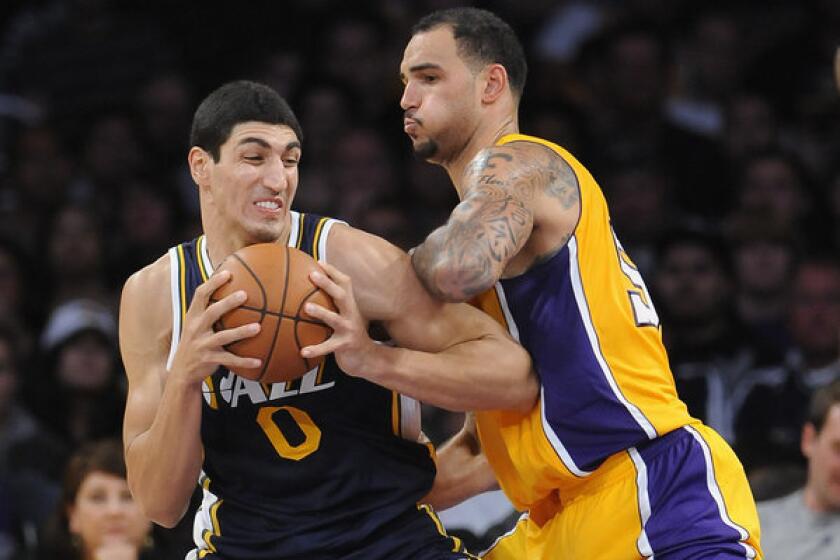 Lakers rookie center Robert Sacre tries to hold his position as Jazz center Enes Kanter works in the post during an exhibition game.