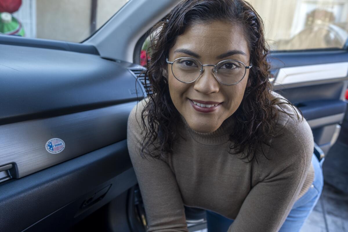 A woman leans into a car that has an "I voted" sticker on the dash.