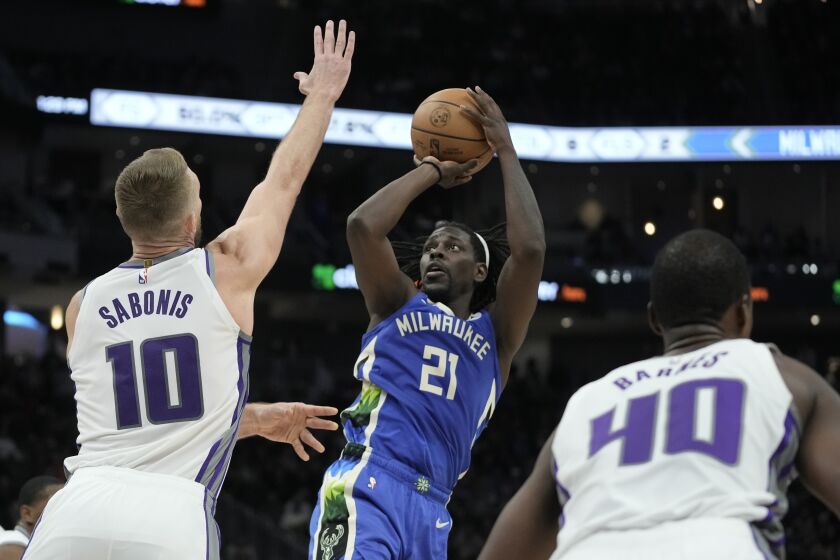 Jrue Holiday, de los Bucks de Milwaukee, toma un tiro sobre Domantas Sabonis, de los Kings de Sacramento, durante la segunda mitad del juego de baloncesto de la NBA, el miércoles 7 de diciembre de 2022, en Milwaukee. (AP Foto/Morry Gash)