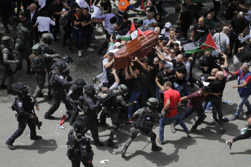 Police and mourners with a casket jostle in the street