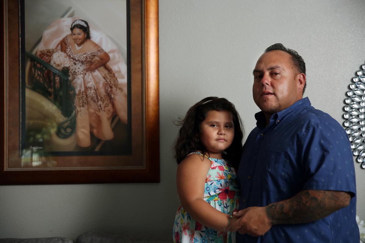Rafael Saavedra and his daughter Gianna, 5. A framed picture of his oldest daughter, Gizzelle, hangs beside them.