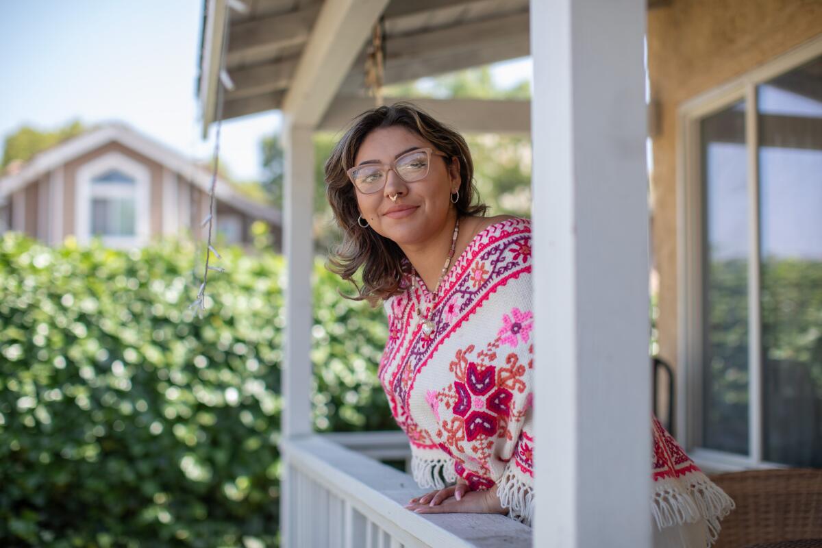Nani Ozelotzin-Hernandez poses for a portrait on the porch of a home. 