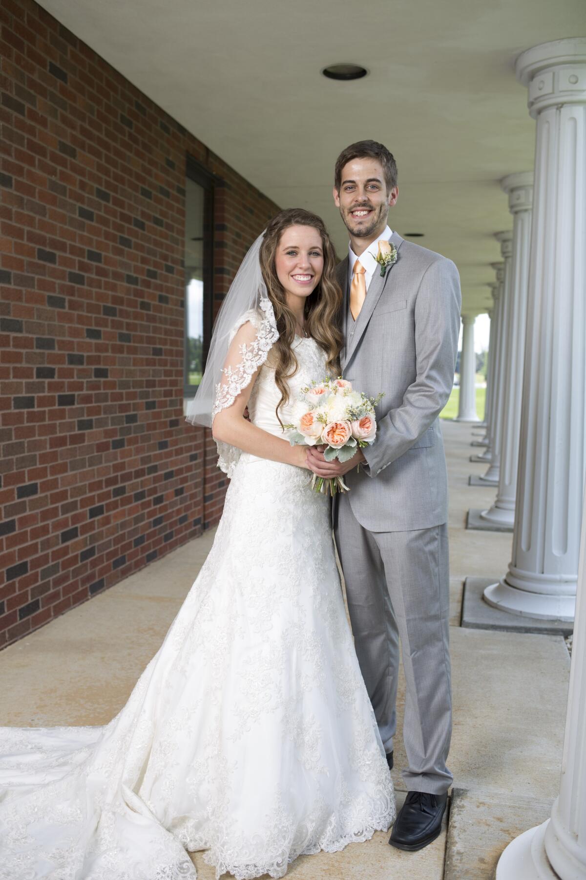 Jill Duggar in a white wedding dress and Derick Dillard in grey suit and tie.