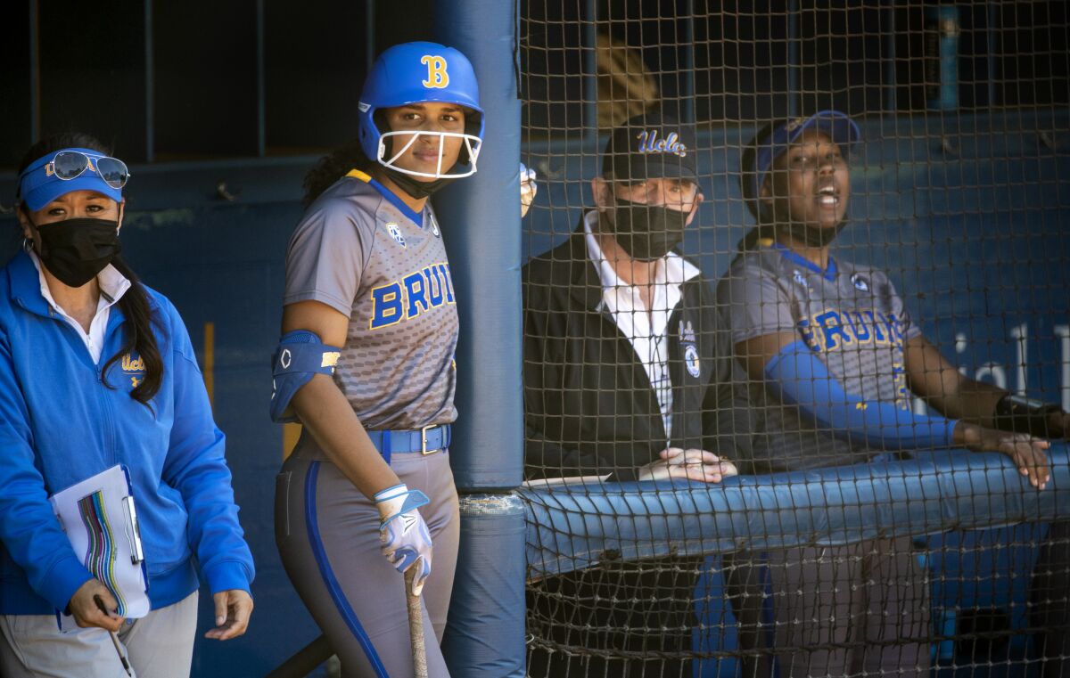 Maya Brady holds a bat outside the UCLA dugout next to head coach Kelly Inouye-Perez
