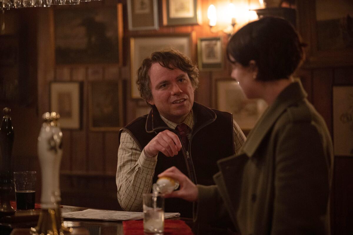 A man, right, talks to a woman pouring herself a drink at a bar