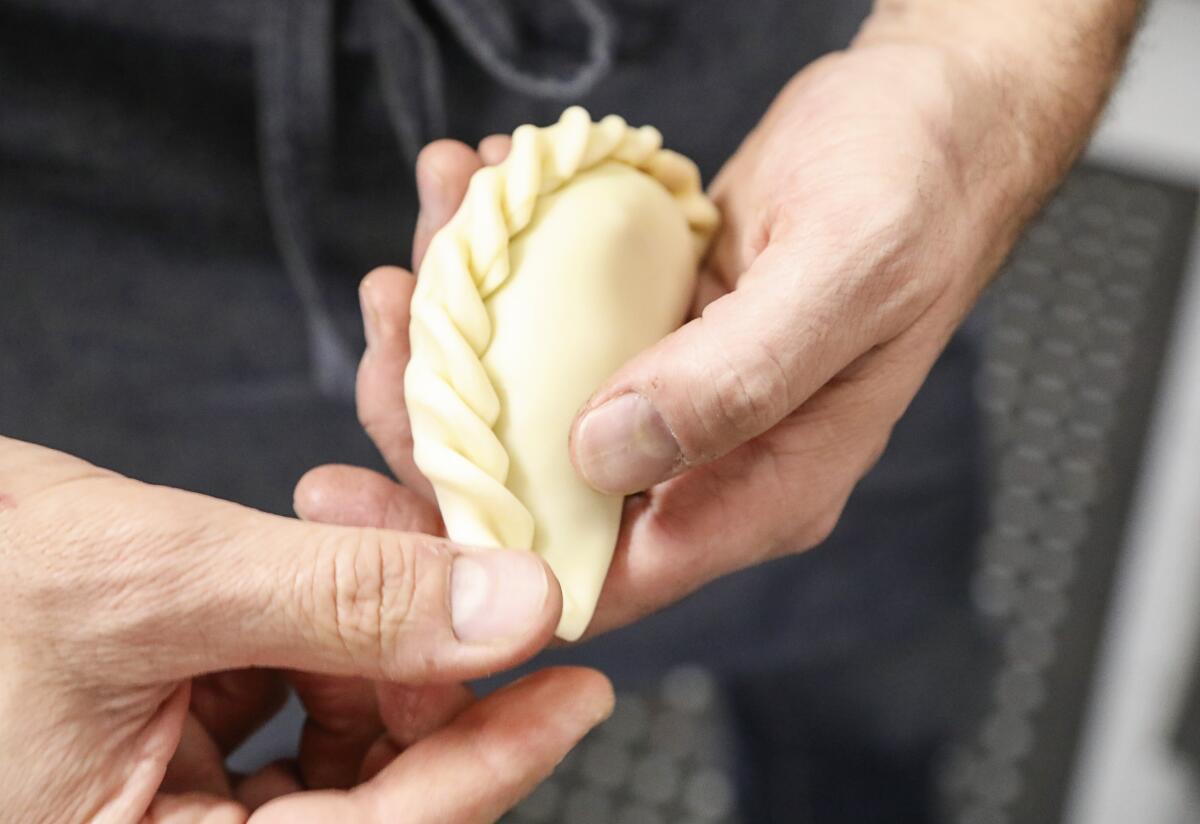 Matias Rigali, owner of Empanada Kitchen, demonstrates one of the techniques for folding the edges of an empanada.