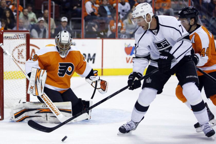 Kings forward Jeff Carter, center, tries to settle the puck in front of Philadelphia Flyers goalie Ray Emery and defenseman Kimmo Timonen, right, during the first period of the Kings' 3-2 road win Monday.