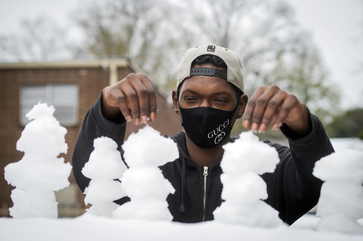 Vinson Parnell, of Jackson, Miss., plays with newly-fallen snow on the top of his brother's car Monday, Jan. 11, 2021. Snow and ice blanketed central Mississippi after an overnight winter storm brought snow and frozen rain to the area, but it quickly melted on the roads with rising temperatures. (Barbara Gauntt/The Clarion-Ledger via AP)