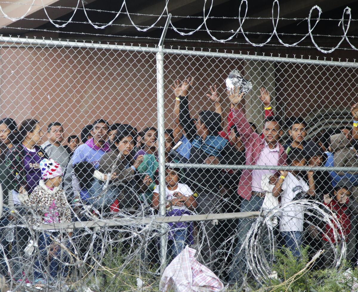 ARCHIVO - En esta fotografía de archivo del 27 de marzo de 2019, migrantes centroamericanos esperan comida en una zona cercada en El Paso, Texas. (AP Foto/Cedar Attanasio, Archivo)