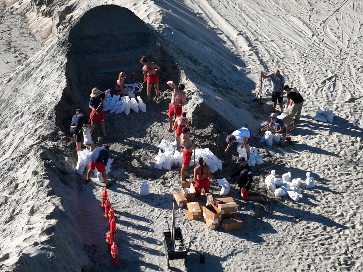 An aerial view of Long Beach lifeguards filling sandbags on the beach.