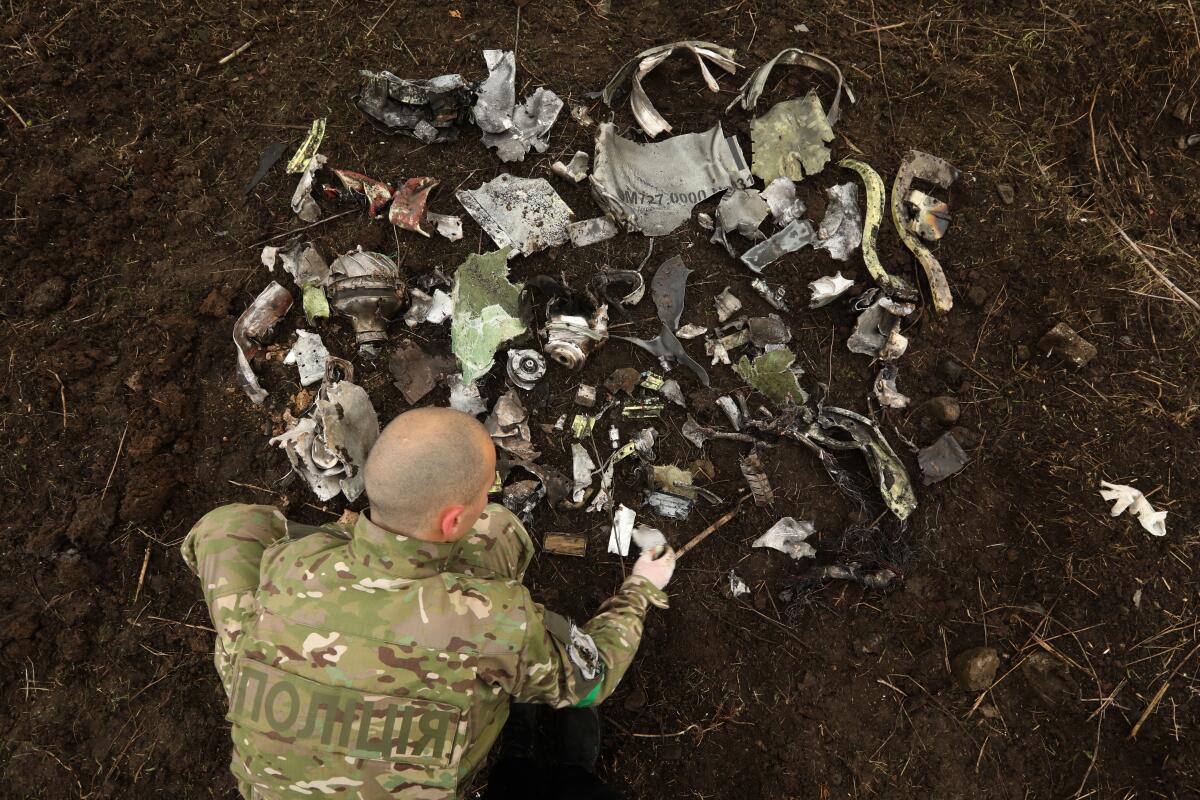 A man in camouflage lays out metal pieces.