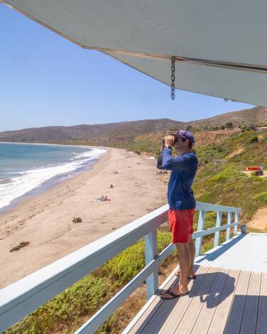 Malibu, CA - June 21: Los Angeles County lifeguard Matt Tomlinson looks over the beach from the lifeguard tower at Nicholas Canyon Beach in Malibu Friday, June 21, 2024. (Allen J. Schaben / Los Angeles Times)