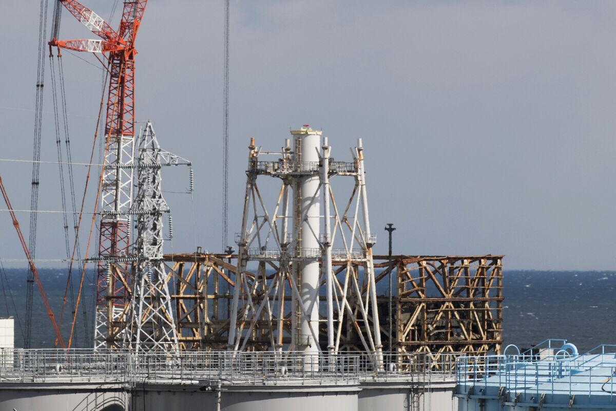 FILE - The damaged Unit 1 reactor, back, and the exhaust stack shared with the Unit 1 and 2 reactors at the Fukushima Daiichi nuclear power plant stand along the coast of Okuma town, Fukushima prefecture, northeastern Japan, Saturday, Feb. 27, 2021. A remote-controlled robot was used on Tuesday, Feb. 8, 2022, to probe the hardest-hit nuclear reactor at Japan's wrecked Fukushima plant, as officials push forward with recovery and clean-up operations that have been mired in delays and controversy. (AP Photo/Hiro Komae, File)