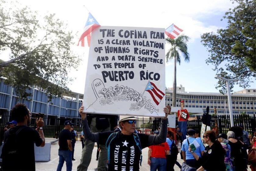 Un hombre sostiene una pancarta durante una manifestación convocada hoy, miércoles 16 de enero de 2018, ante el Tribunal Federal en San Juan (Puerto Rico) para mostrar el rechazo al acuerdo alcanzado entre el Gobierno puertorriqueño y los acreedores Cofina. EFE