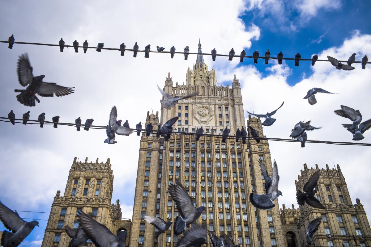 Pigeons take flight as others are perched in front of the Russian Foreign Ministry building.