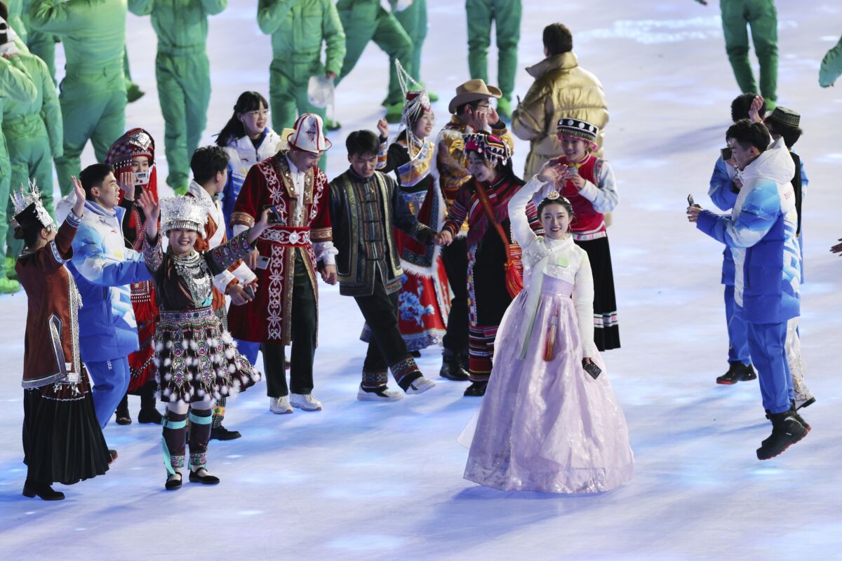 A performer, second from right, clad in a traditional Korean dress waves during the opening ceremony of the 2022 Winter Olympics in Beijing, China, Friday, Feb. 4, 2022. Major South Korean presidential candidates accused China of laying claim to their culture after the performer wore white and light purple hanbok dress during the opening of the Beijing Winter Olympics. (Lim Hwa-young/Yonhap via AP)