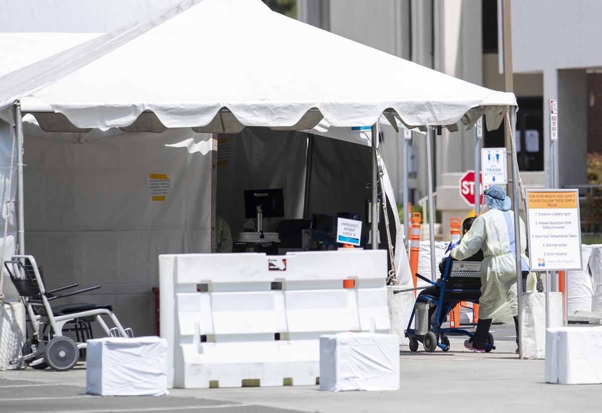 A medical professional wheels a patient into a tent outside the emergency room of Fountain Valley Regional Hospital & Medical Center on Thursday.