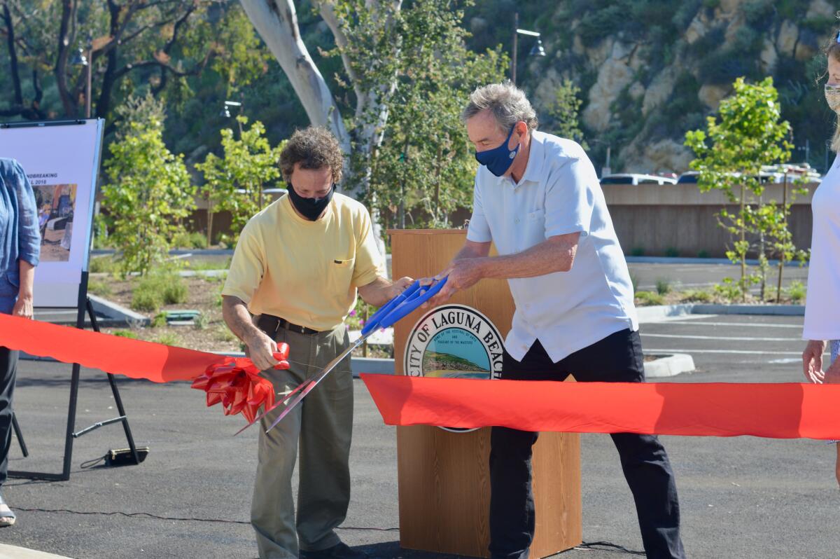 Mayor Pro Tem Steve Dicterow, left, helps Mayor Bob Whalen, right, cut the ceremonial ribbon for the Village Entrance.