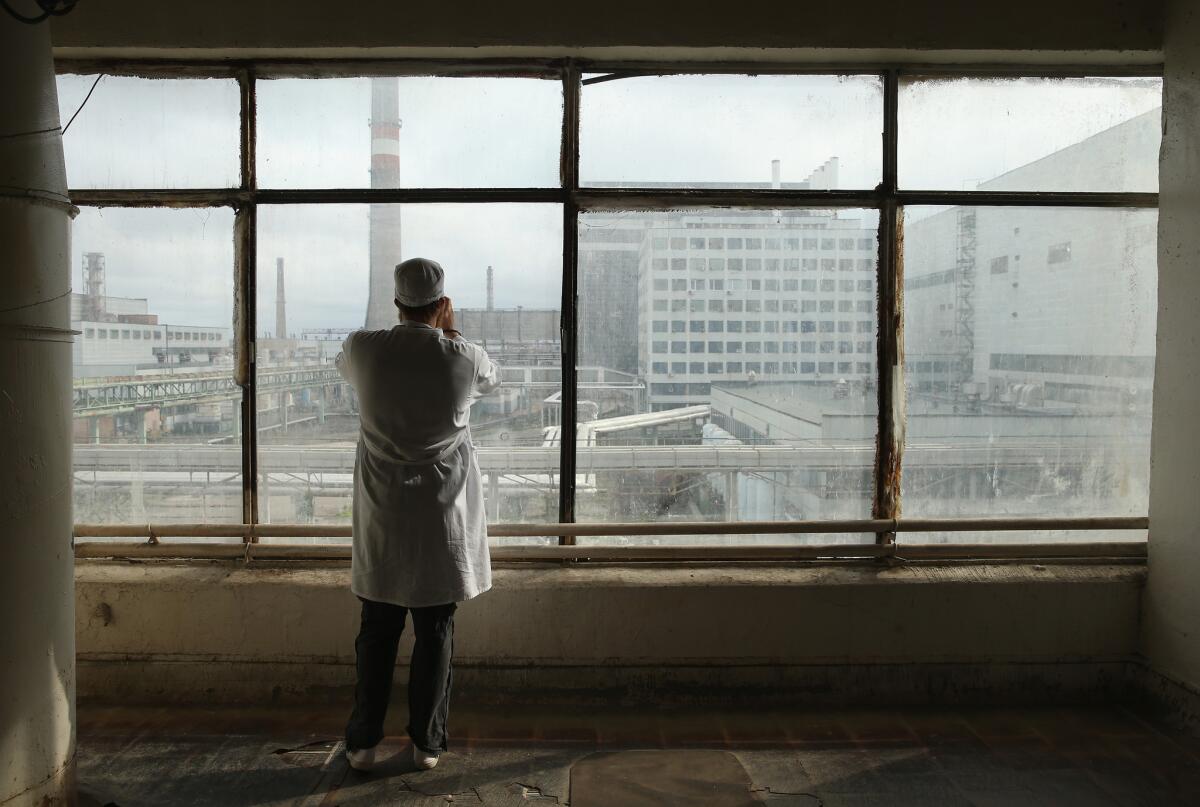CHORNOBYL, UKRAINE - SEPTEMBER 29: A visitor touring the former Chernobyl nuclear power plant takes a photo through a window looking towards facilities that house reactors one and two on September 29, 2015 near Chornobyl, Ukraine. The Chernobyl plant is currently undergoing a decades-long decommissioning process of reactors one, two and three, which continued operation for years following the accident at reactor four. On April 26, 1986, technicians at Chernobyl conducting a test inadvertently caused reactor number four, which contained over 200 tons of uranium, to explode, flipping the 1,200 ton lid of the reactor into the air and sending plumes of highly radioactive particles and debris into the atmosphere in a deadly cloud that reached as far as western Europe. 32 people, many of them firemen sent to extinguish the blaze, died within days of the accident, and estimates vary from 4,000 to 200,000 deaths since then that can be attributed to illnesses resulting from Chernobyl's radioactive contamination. Today large portions of the inner and outer Chernobyl Exclusion Zone that together cover 2,600 square kilometers remain contaminated. A consortium of western companies is building a movable enclosure called the New Safe Confinement that will cover the reactor remains and its fragile sarcophagus in order to prevent further contamination. (Photo by Sean Gallup/Getty Images)