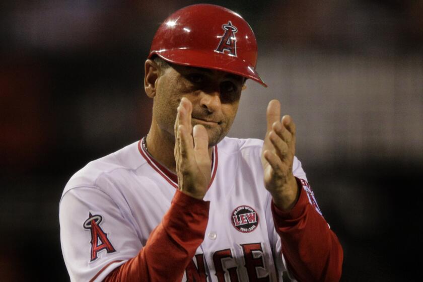Angels third base coach Dino Ebel claps during a game against the Seattle Mariners in June 2013. Ebel, now the Angels' bench coach, will be an instructor at a baseball clinic in Upland on Sunday.