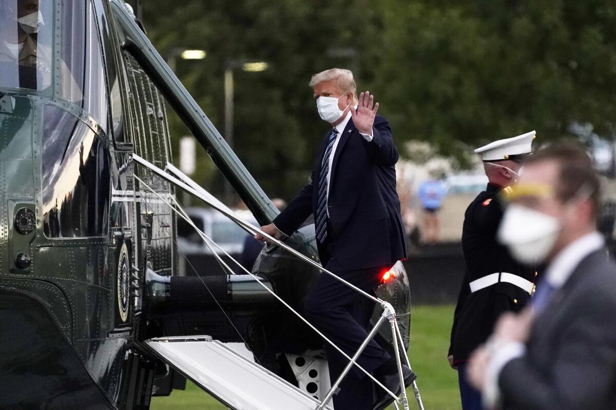 President Donald Trump wears a mask and waves as he boards the Marine One helicopter to return to the White House 