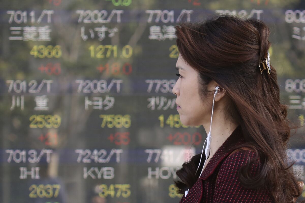 A woman walks by an electronic stock board of a securities firm in Tokyo, Tuesday, Nov. 5, 2019. Asian shares have advanced after the Dow Jones Industrial Average returned to a record high. Benchmarks rose across the region, led by a 2% jump in Japan’s Nikkei 225 index. (AP Photo/Koji Sasahara)
