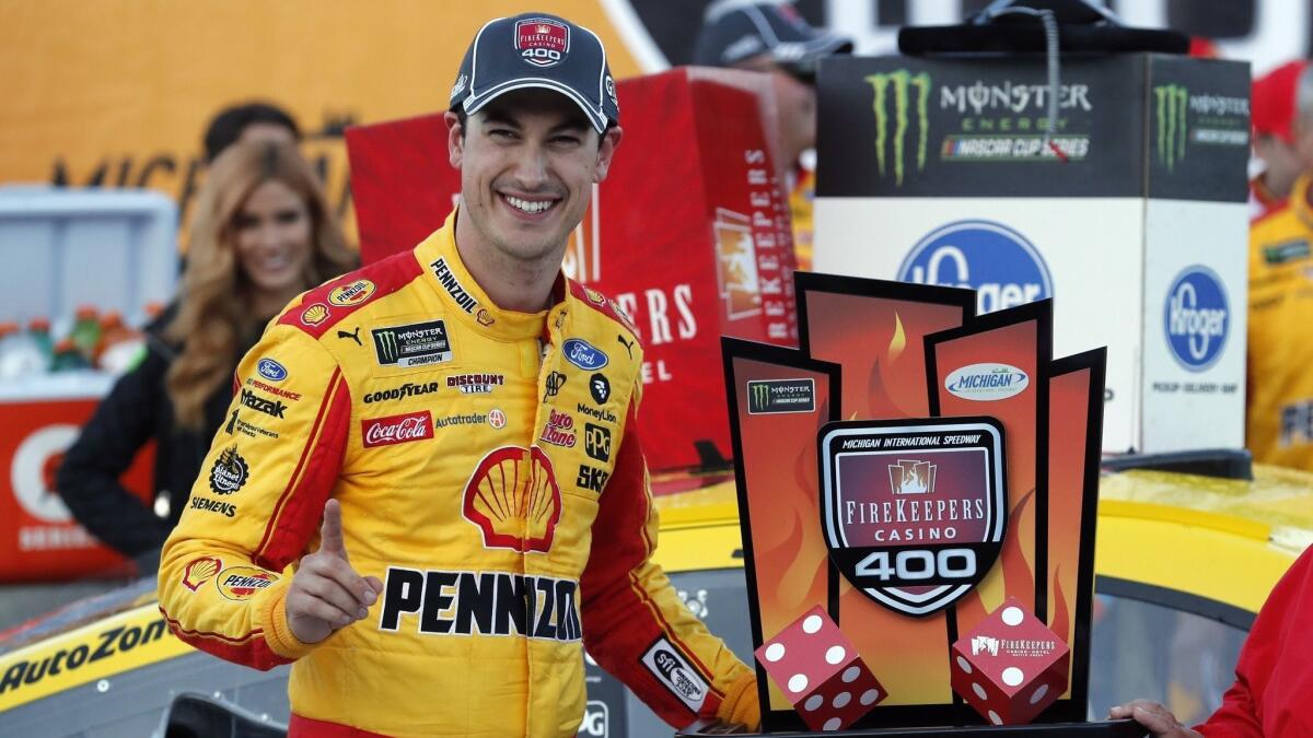 Joey Logano stands with the trophy after winning a NASCAR Cup Series race at Michigan International Speedway on June 10.