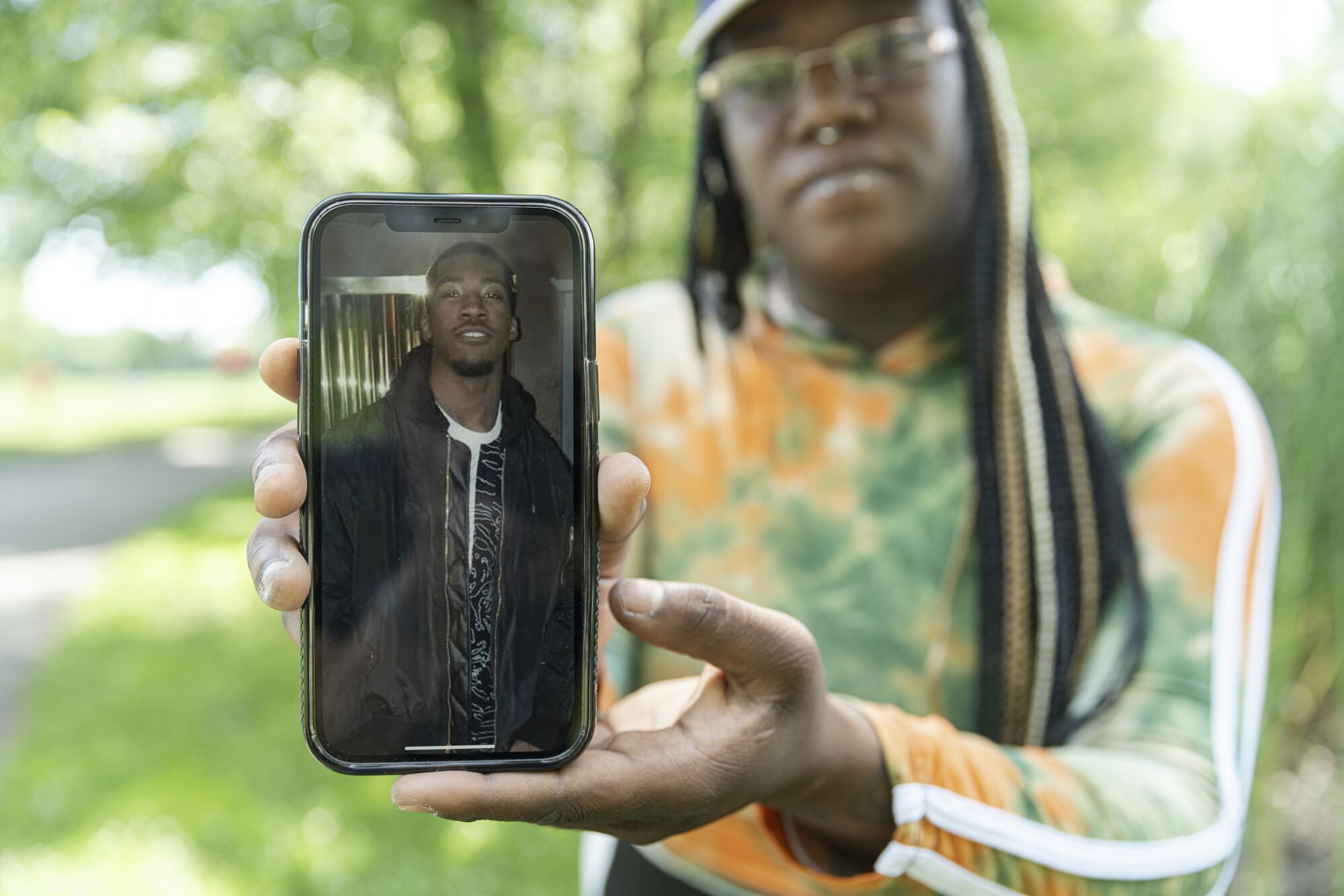 A woman holds up a phone with a photo of a man