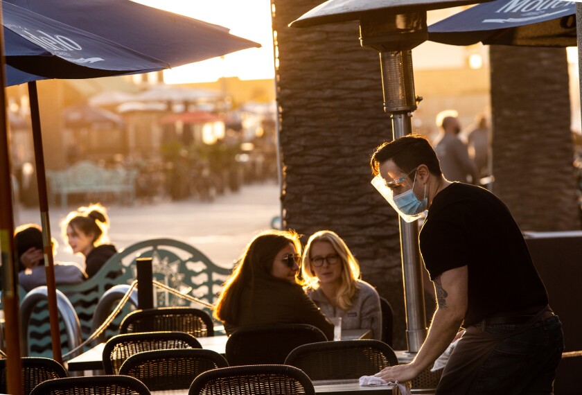 A server at Rebel Republic in Hermosa Beach cleans tables on Nov. 25, just before restaurants shut down in L.A. County. 
