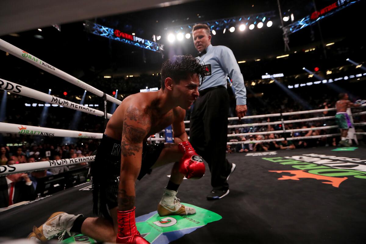 Ryan Garcia grimaces in pain after taking a body shot from Gervonta Davis in the seventh round.