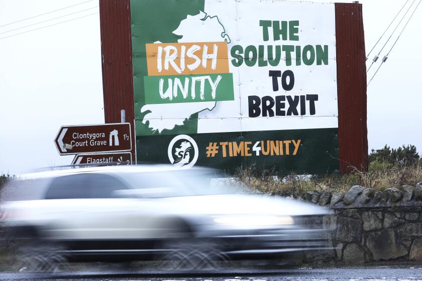 A motorist passes an anti Brexit poster on the Irish border between Republic of Ireland and Northern Ireland, close to the village of Jonnesborough Thursday, Dec. 31, 2020. (AP Photo/Peter Morrison)