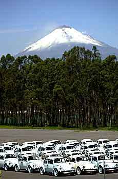 The Popocatepetl volcano looms in the background as some of the final Volkwagen Beetles are stored outside the factory in Puebla, Mexico.