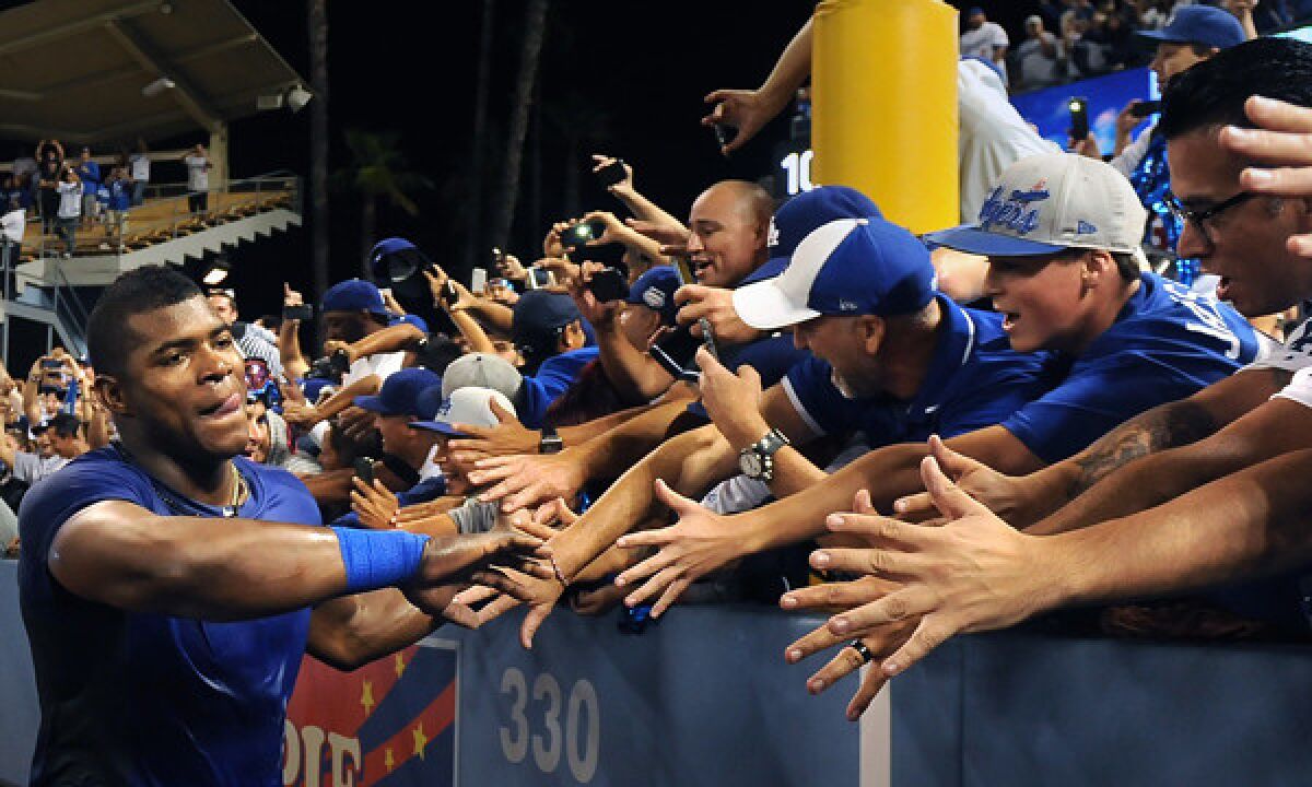 Dodgers right fielder Yasiel Puig celebrates with fans after the team's win over the Atlanta Braves in Game 4 of the National League division series at Dodger Stadium on Oct. 7, 2014.