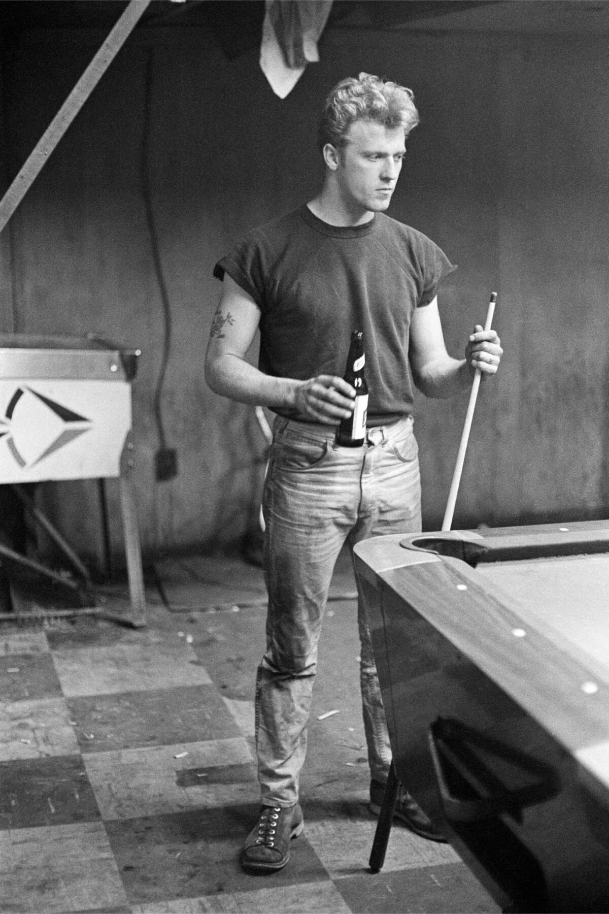 A man with a beer plays pool.