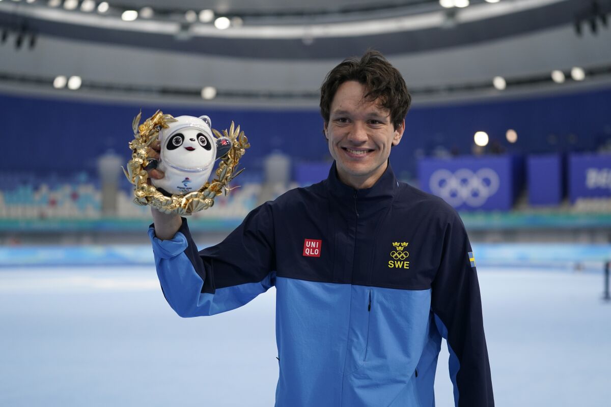 Nils van der Poel of Sweden, poses during a venue ceremony after winning the gold medal and breaking his own world record in the men's speedskating 10,000-meter race at the 2022 Winter Olympics, Friday, Feb. 11, 2022, in Beijing. (AP Photo/Ashley Landis)