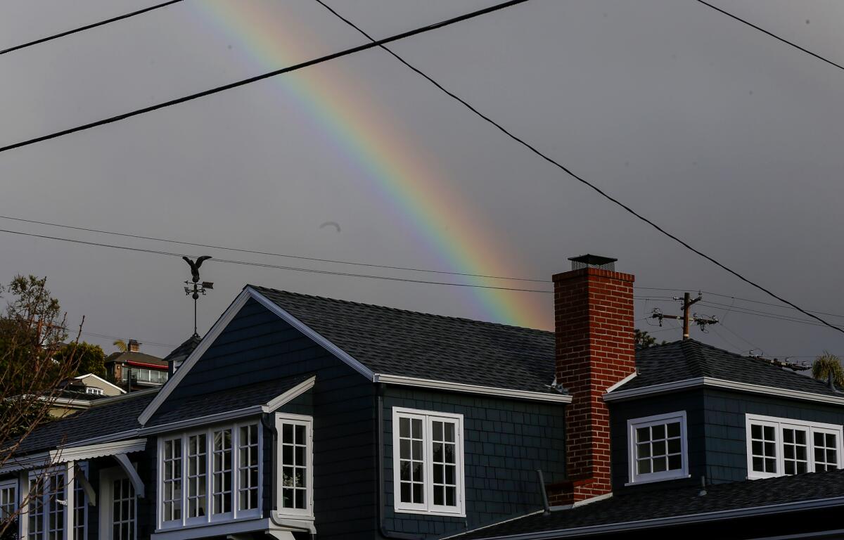 A full rainbow appears in a beam of sunlight as a rain storm flurry passes overhead.