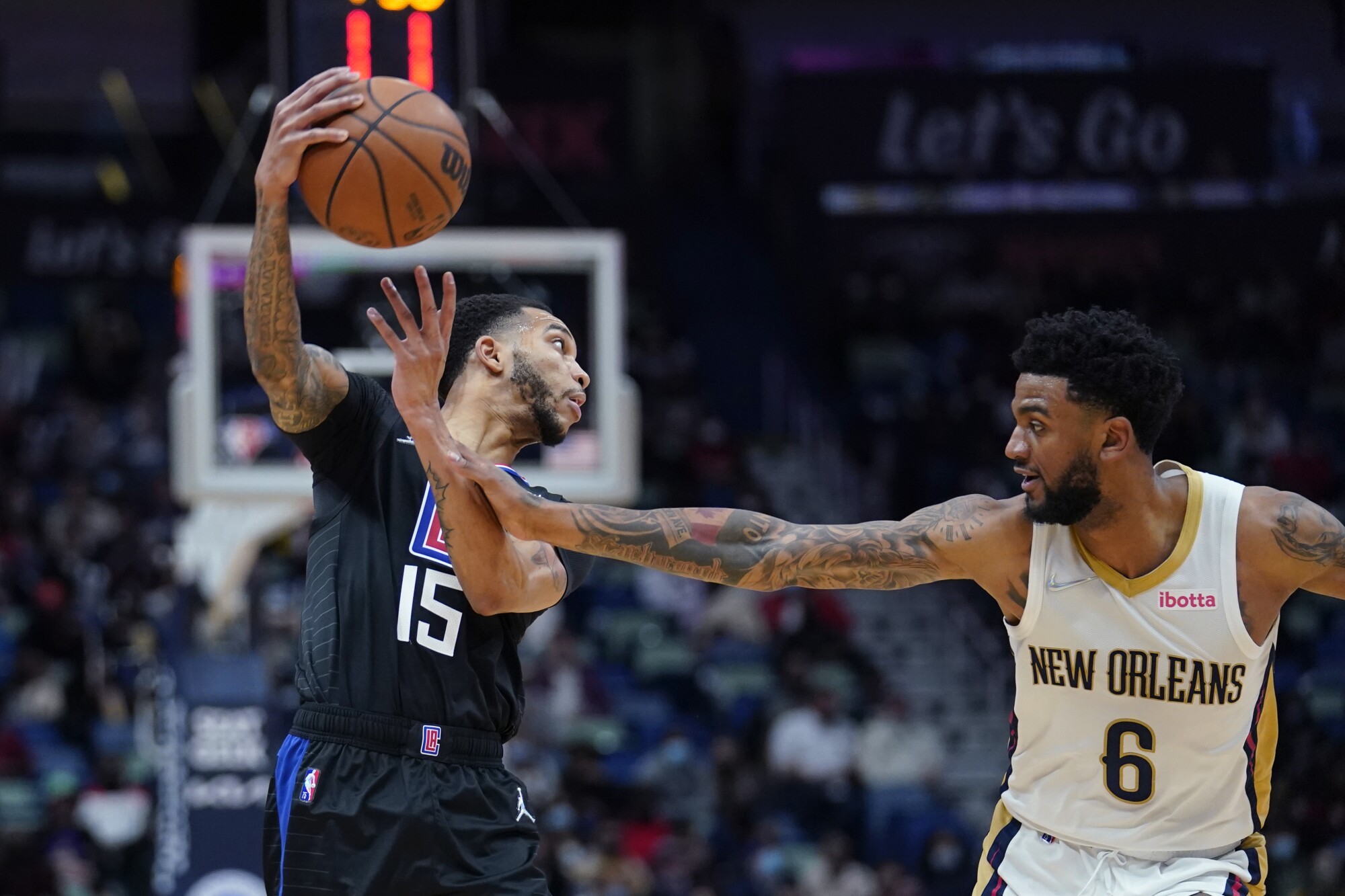 Clippers guard Xavier Moon lifts his right arm to try to pass as Pelicans guard Nickeil Alexander-Walker grabs his left arm.