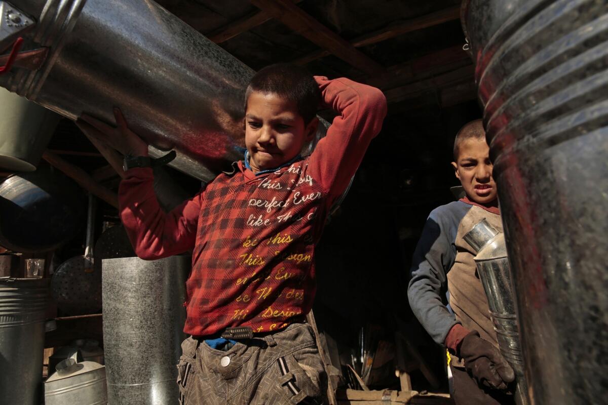 Brothers Hekmat, 12, left, and Qudratulla, 9, work in a metal shop in Kabul, where they help make water heaters and other items. Hekmat started working at age 8 when his father told him he should learn a trade. He attends class in the afternoon and is now in the third grade; Qudratulla is in second grade.