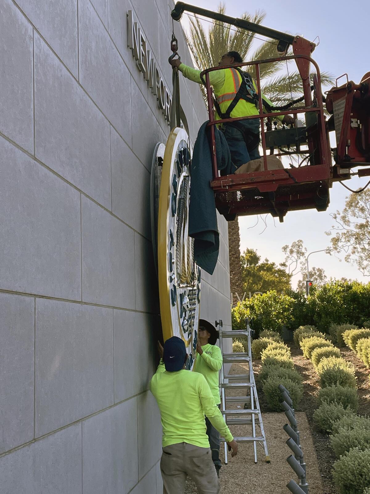 A Newport Beach work crew installs a city seal outside City Hall on May 8.